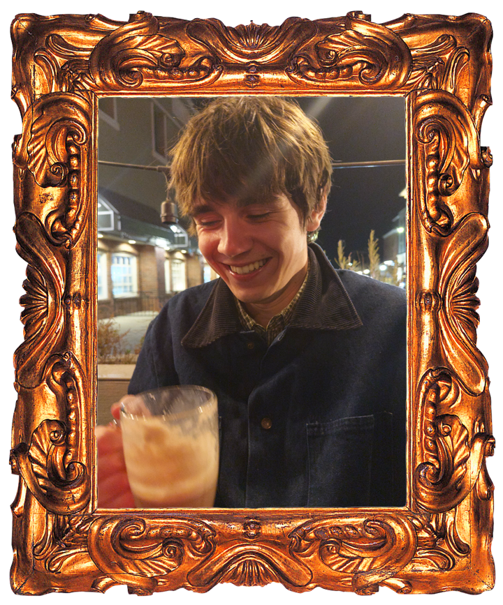 Charlie Andrade laughing over an iced chai on a patio at night